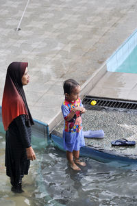 Rear view of siblings standing in water