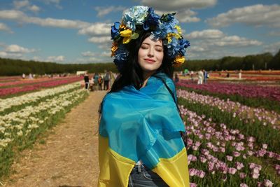 Portrait of young woman standing on field with the ukrainian flag