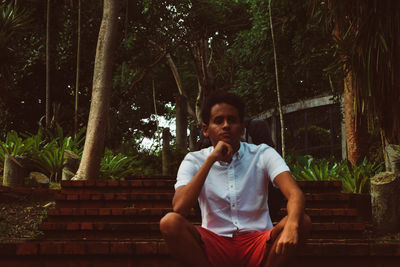 Young man sitting on tree