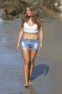Beautiful young woman walking at beach