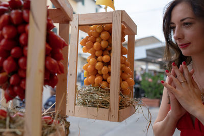  woman with hands clasped looking at fruits at market stall