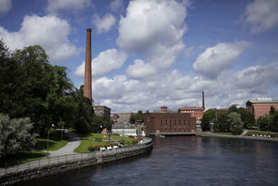 Buildings by river against sky in city