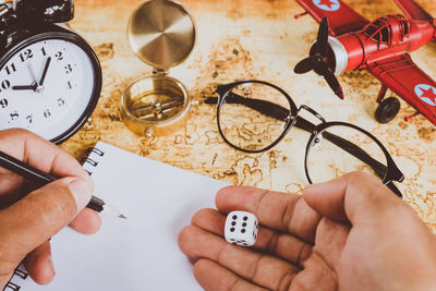 Cropped hand holding dice over book on table