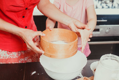 Midsection of mother and daughter holding sieve