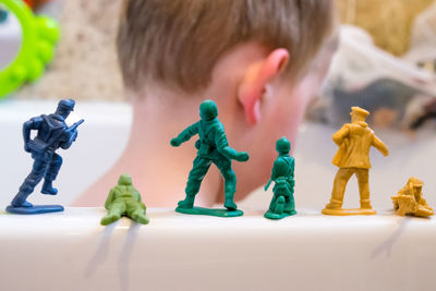 Close-up of boy by toy soldiers on bathtub