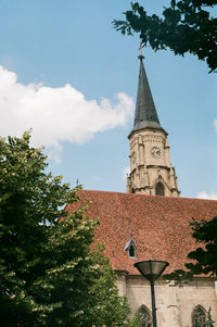 Low angle view of trees and building against sky