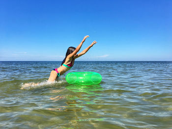 Playful girl swimming in sea against sky