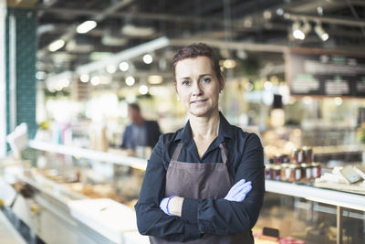Portrait of confident female owner standing arms crossed in supermarket