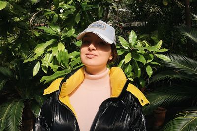 Portrait of young woman standing against plants