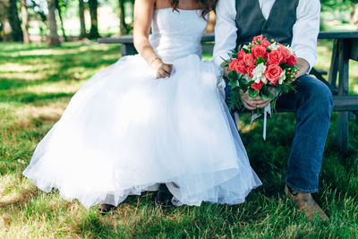 Midsection of couple holding flower bouquet