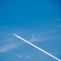 Low angle view of vapor trails in blue sky
