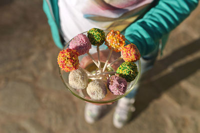 Low section of woman holding colorful lollipops on field