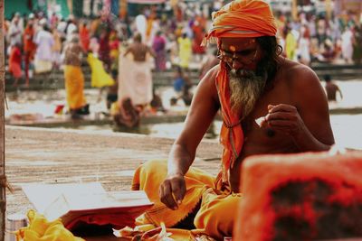 Shirtless sadhu praying at riverbank during kumbh mela