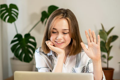 Young smiling woman having video call on laptop at home. girl greeting friends on a video chat.