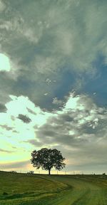 Scenic view of grassy field against cloudy sky