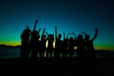 Silhouette people standing in sea against clear sky