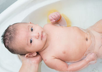 Cropped hand of mother bathing son at home