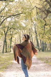 Young brown-haired woman on a road in the middle of a forest in autumn