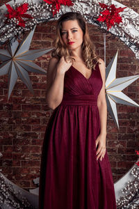 Portrait of young woman standing against wall