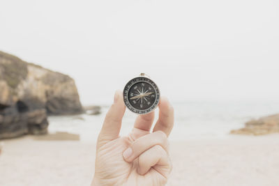 Close-up of hand holding navigational compass at beach