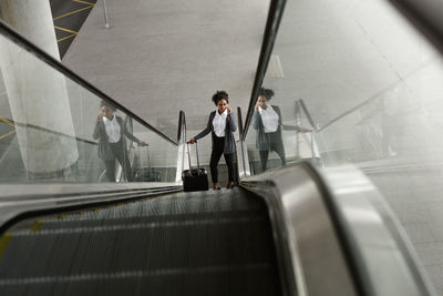 High angle view of businesswoman standing on escalator at airport