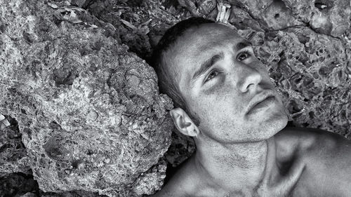 Close-up of depressed young man sitting by rocks