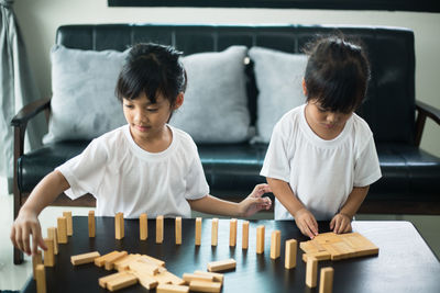 Siblings playing with toy blocks on table