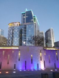 Low angle view of illuminated cityscape against clear blue sky