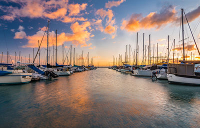 Boats moored at harbor against sky during sunset