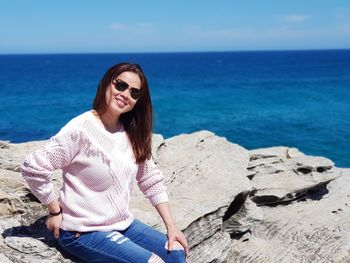 Young woman sitting on rock by sea