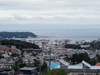 High angle view of townscape by sea against sky