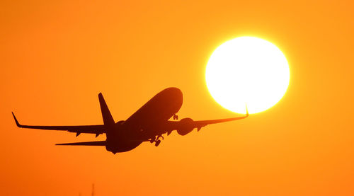 Silhouette airplane against sky during sunset