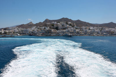 Scenic view of sea by buildings against clear blue sky