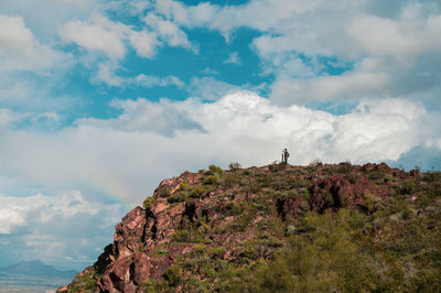 Distant of man standing on mountain against cloudy sky