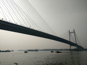 Suspension bridge over river against sky