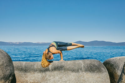 Young woman practicing yoga on lake tahoe in northern california.