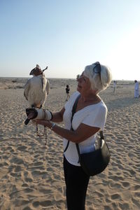 Woman with falcon perching on her arm in the dubai desert. 