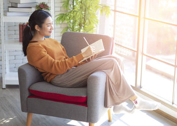 Young woman sitting on sofa at home