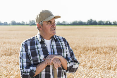 Portrait of senior farmer standing in front of a field looking at distance