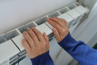 Closeup of woman warming her hands on the heater at home during cold winter days. heating season.