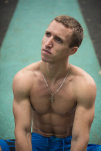 Portrait of shirtless young man exercising in gym