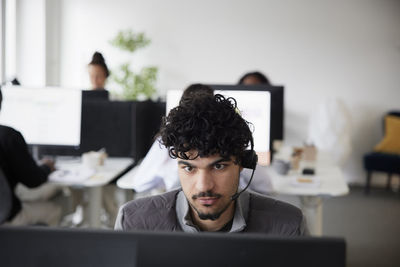 Man wearing headset using desktop pc in office