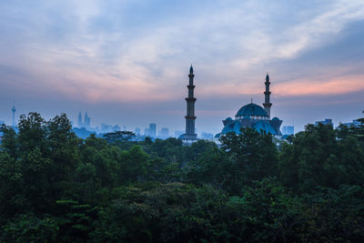 Trees and buildings against sky during sunset