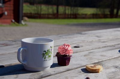 Coffee by cupcake on wooden table