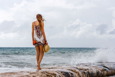 Rear view of young woman standing at beach