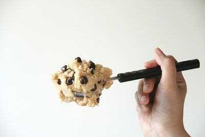 Close-up of hand holding cookies against white background