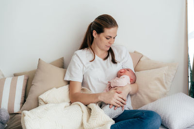 Young caucasian mother with a one-month baby in her arms.