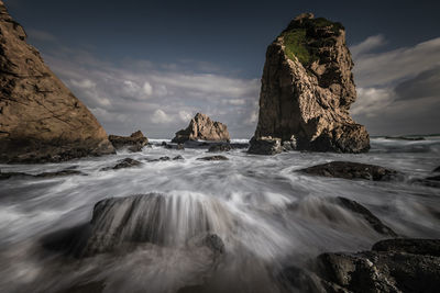 Scenic view of rock formation in sea against sky