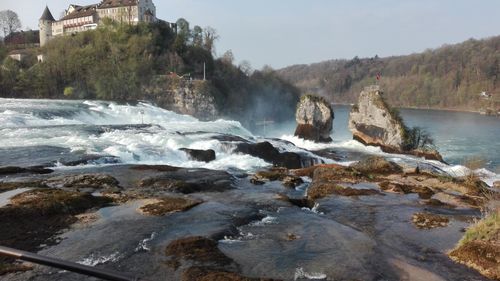 Scenic view of waterfall by sea against clear sky