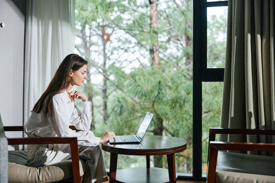 Young woman using laptop while sitting on sofa at home